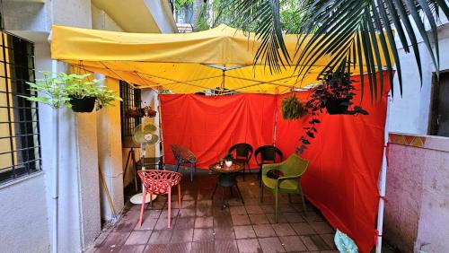 a patio with a table and chairs and a yellow and red tent at Rostel Backpackers Hostel in Pune