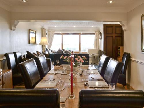 a dining room with a long table and leather chairs at Woodend Bungalow in Hucknall under Huthwaite