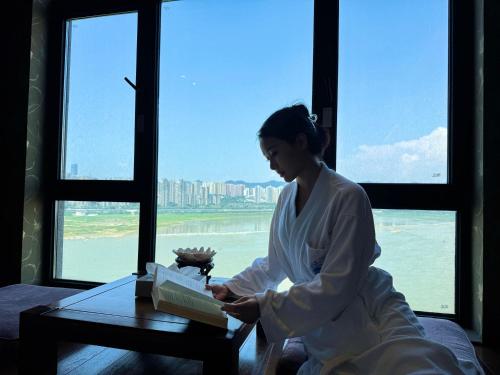 a woman opening a gift in front of a window at Chongqing Jiayu Emperor Hotel in Jiulongpo