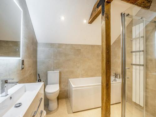 a bathroom with a toilet and a tub and a sink at Stable End in Whitchurch