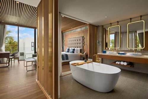 a bathroom with a tub and a bedroom with a bed at Hoi An Royal Beachfront Villas in Dien Ban