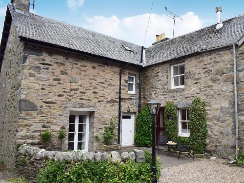 an old stone house with a white door at Toadhall in Aberfeldy