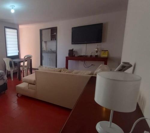 a living room with a white couch and a tv at Flowers House Aptos - Centro Histórico in Valledupar