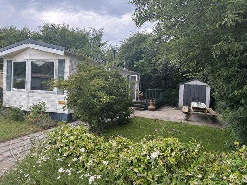 a small white house with a picnic table in a yard at KD 743 - Vakantiepark Kijkduin in The Hague