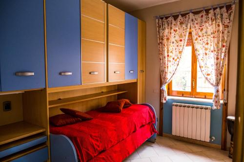 a bedroom with a red bed and a window at Luc's Home in Frattaminore