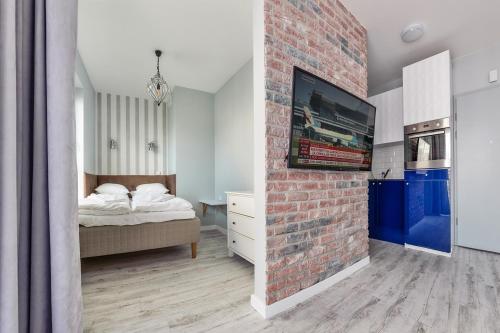 een slaapkamer met een bakstenen muur, een bed en een tv bij Perfect Apartment Chmielna Park in Gdańsk