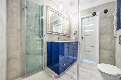 een badkamer met een blauwe wastafel en een douche bij Perfect Apartment Chmielna Park in Gdańsk