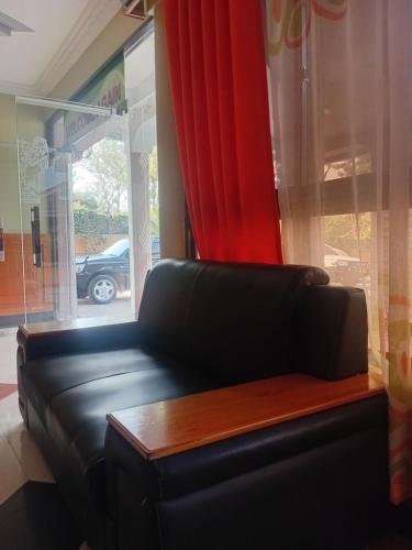 a black leather couch sitting in front of a window at New Tourist Hotel in Mwanza