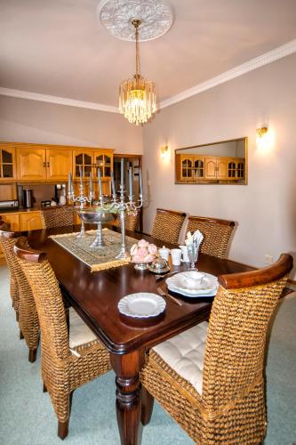 a dining room with a wooden table and wicker chairs at Sewende Hemel in Kroonstad