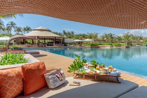 a resort pool with a table with food on it at Fusion Resort Cam Ranh - All Spa Inclusive in Cam Ranh