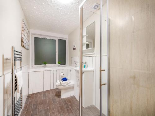 a white bathroom with a toilet and a window at Argyle House in Rothesay