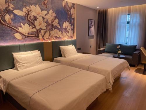 two beds in a hotel room with a painting on the wall at Jinjiang Inn Wuhan Linjiaohu Wanda Branch in Wuhan