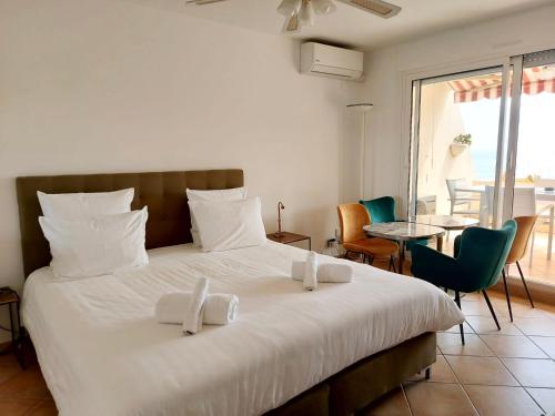 a bedroom with a large white bed with chairs and a table at Mansfield vue carte Postale Terrasse Piscine calme port à 200m à pied in Menton