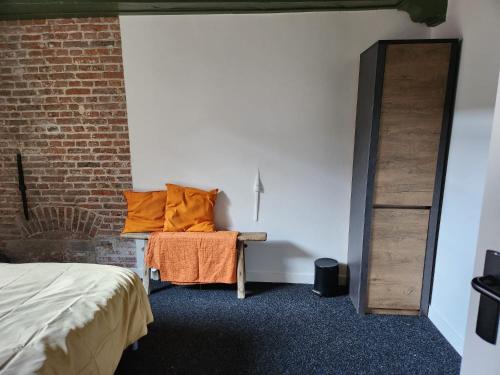 a bedroom with a bench with orange pillows on it at Stadslogement Bij de Sassenpoort in Zwolle