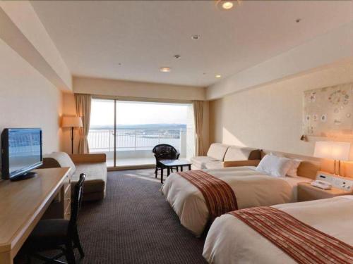 a hotel room with two beds and a desk with a computer at Hotel Harvest Nankitanabe in Tanabe
