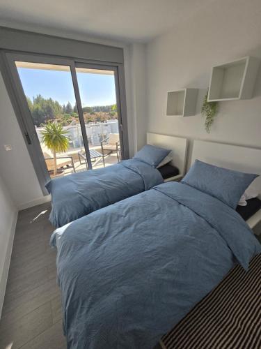 2 bedden in een slaapkamer met een groot raam bij Appartement Mijas in Mijas Costa
