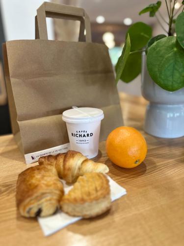 a table with a bagel and an orange and a cup of coffee at Hotel Chantereyne in Cherbourg en Cotentin