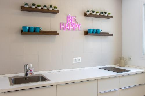 a kitchen with a sink and a happy sign on the wall at La Familia Beach Houses La Cala in La Cala de Mijas