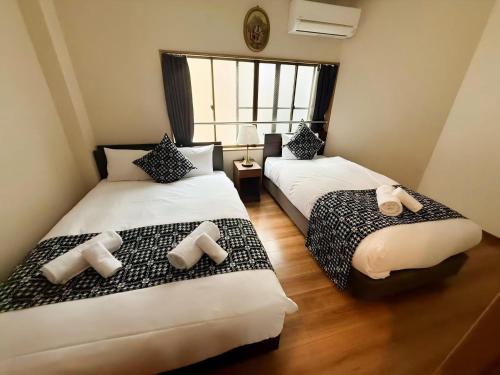 two beds in a small room with a window at 最大8名で泊まれる貸別荘日本橋駅徒歩5分黒門市場に隣接し道頓堀難波心斎橋徒歩圏内 in Osaka