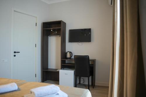 a bedroom with a desk and a chair and a television at Hotel BABU in Kutaisi