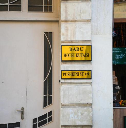 a yellow sign on the side of a building at Hotel BABU in Kutaisi
