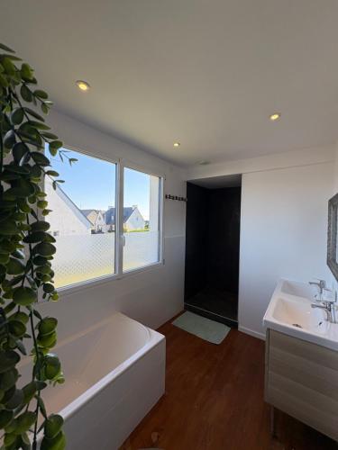 ein Badezimmer mit Badewanne und Waschbecken und einem Fenster in der Unterkunft Charmante Maison Néo-bretonne in Perros-Guirec
