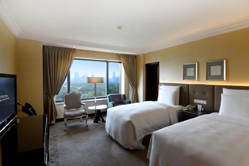 a hotel room with two beds and a television at The Kunlun Beijing Jin Jiang Radisson in Beijing