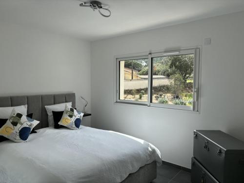 une chambre blanche avec un lit et une fenêtre dans l'établissement Appartement T2 vue mer et citadelle, à Calvi