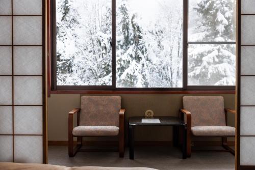 a room with two chairs and a table and a window at Kogakuro in Myoko