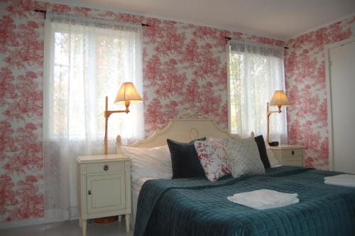 a bedroom with a bed with red floral wallpaper at STF Vickleby Bo Pensionat in Färjestaden
