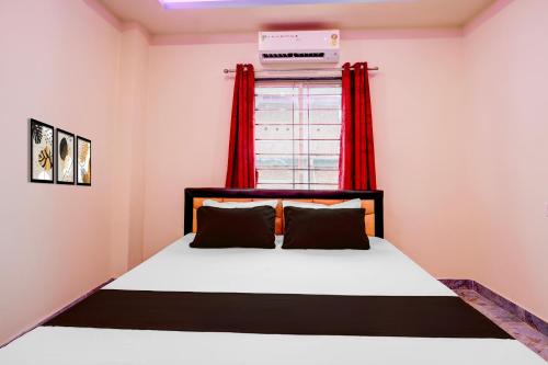 a bedroom with a bed and a window with red curtains at Hotel O The Silver Stone in Guwahati
