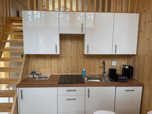 a kitchen with white cabinets and a sink at Perła in Stegna
