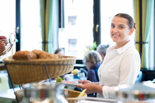 a woman holding a plate with a basket of food at HOTEL Am Spichernplatz in Düsseldorf