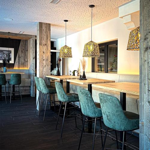 a bar with green chairs in a restaurant at Wander- und Familienhotel Erika in Wagrain