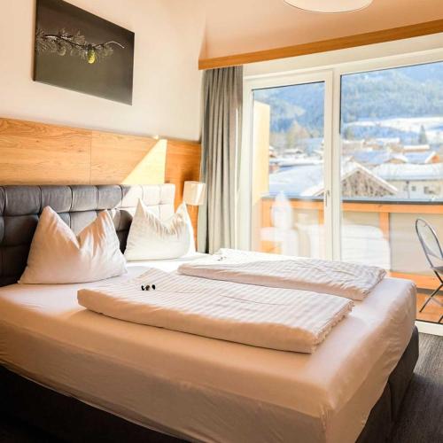 a large bed in a hotel room with a large window at Wander- und Familienhotel Erika in Wagrain