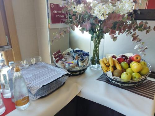a counter with two bowls of fruit and a vase of flowers at Kairos Garda Hotel in Castelnuovo del Garda