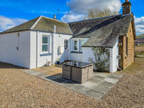 a white house with a stone driveway in front of it at Myreside Cottage in Meigle