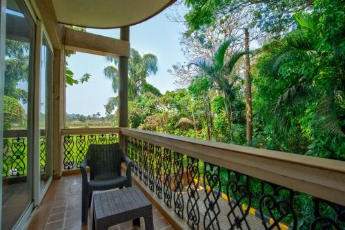 a room with a balcony with a chair and trees at Aveeno Villas with Swimming Pool Near Calangute & Baga in Sangolda