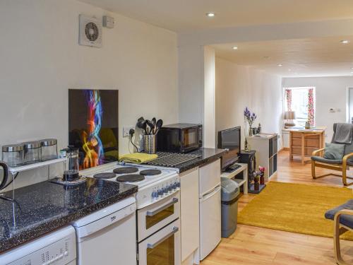 a kitchen with a stove top oven next to a living room at The Barnsdale in Amlwch