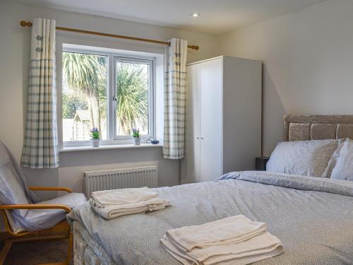 a bedroom with a bed with a chair and a window at The Barnsdale in Amlwch