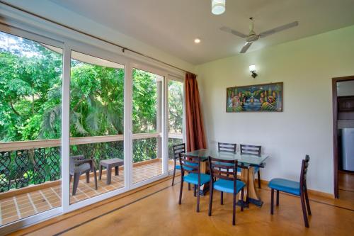 a dining room with a table and chairs and large windows at Aveeno Villas with Swimming Pool Near Calangute & Baga in Sangolda