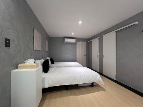 a bedroom with a white bed and a gray wall at Jasmin錦町 1F in Takamatsu