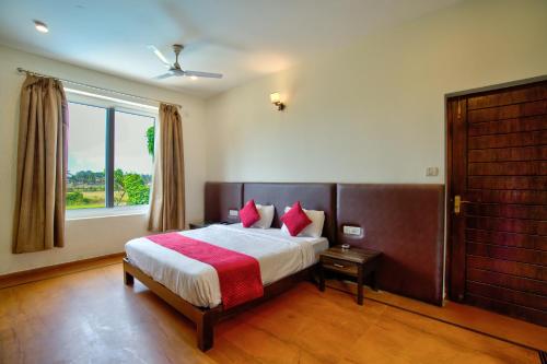 a bedroom with a bed with red pillows and a window at Aveeno Villas with Swimming Pool Near Calangute & Baga in Sangolda