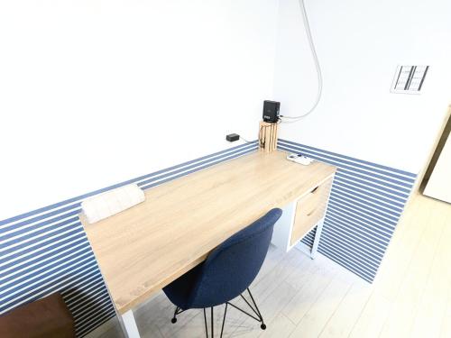 a wooden desk with a blue chair in a room at Backshore 99 in Kujukuri