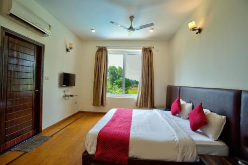 a bedroom with a large bed with red pillows and a window at Aveeno Villas with Swimming Pool Near Calangute & Baga in Sangolda