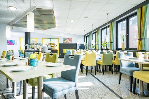 a dining room with tables and yellow chairs at HOTEL Am Spichernplatz in Düsseldorf
