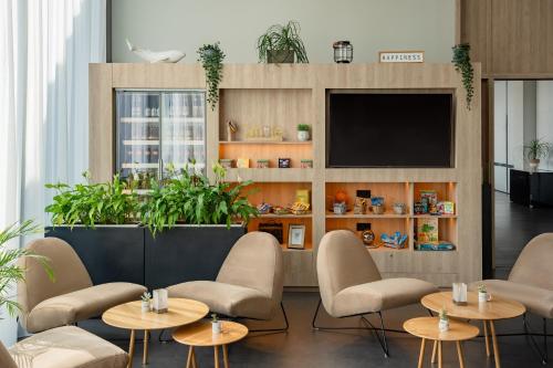 a waiting room with tables and chairs and a tv at INNSiDE by Meliá Bremen in Bremen