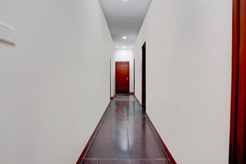 a corridor with a red door in a white hallway at SPOT ON Sj Comforts Boarding And Lodging in Jigani