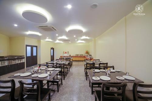 a dining room with wooden tables and chairs at RivieraaHotel in Pondicherry