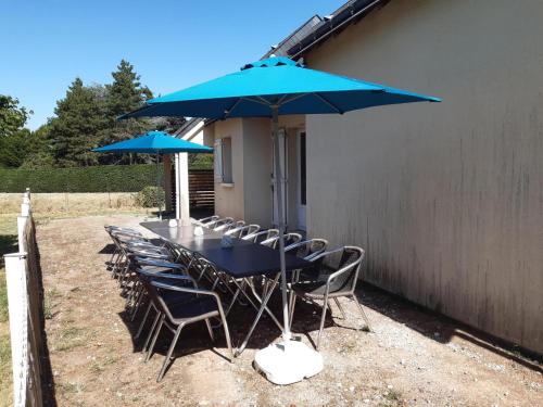a table with chairs and a blue umbrella at Camping Onlycamp les Bords de Vienne in L'Ile-Bouchard